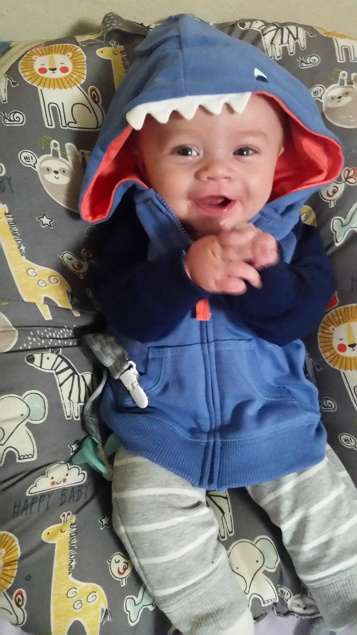 Tate is registered to the contest to win money with this photo: baby, baby_carriage, baby_products, baby_toddler_clothing, child, cool, electric_blue, facial_expression, fashion_accessory, fun, happy, headgear, headwear, outerwear, pattern, person, personal_protective_equipment, sitting, sleeve, smile