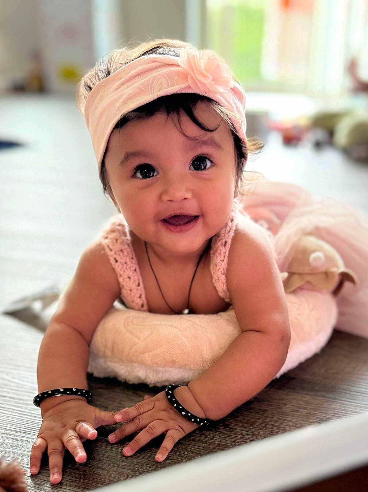 Fiyana joined the competition — help win amazing prizes! baby, child, smile, headband, pink, cushion, floor, indoors, cute, face, hands, knitted, jewelry, bracelets, portrait, happy, toddler, person, bright, soft