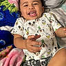 Akon is registered to the contest to win money with this photo: baby, babylaughing, bed, blanket, clothing, cushion, electronics, face, furniture, happy, head, homedecor, laughing, person, phone, photography, portrait, quilt, sitting, smile