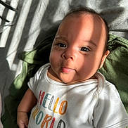 Jacqueline joined the competition — help win amazing prizes! baby, infant, child, onesie, clothing, text, hello_world, face, tongue, expression, sunlight, shadow, skin, eyes, indoor, blanket, green, white, cute, portrait