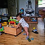 toddler, child, toy_box, toys, wooden_floor, living_room, socks, clothing, furniture, shoes, baby, indoor, person, play, cabinet, television, bucket, exercise_equipment, window, door