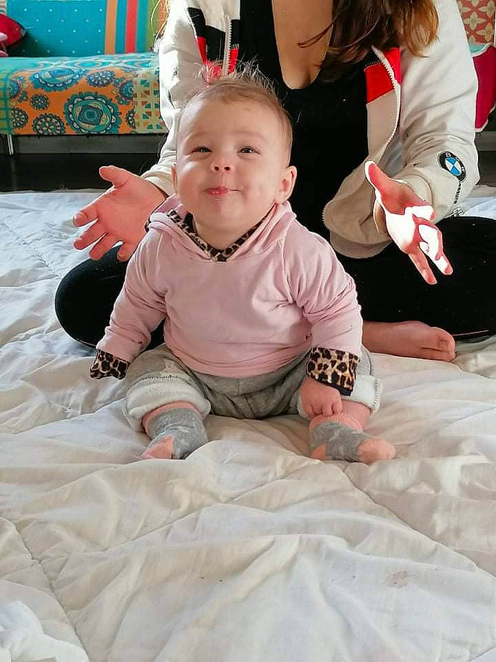 Wendy participe au concours pour gagner de l'argent avec cette photo : baby, baby_toddler_clothing, carpet, child, comfort, event, flooring, fun, happy, head, leisure, linens, people, person, pink, room, sitting, skin, smile, toddler