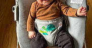 Kayden is registered to the contest to win money with this photo: baby, child, smiling, baby_rocker, toddler, infant, clothing, socks, wooden_floor, monkey_design, turtle_design, cozy, happy, seated, indoor, playful, cute, portrait, bright, comfortable