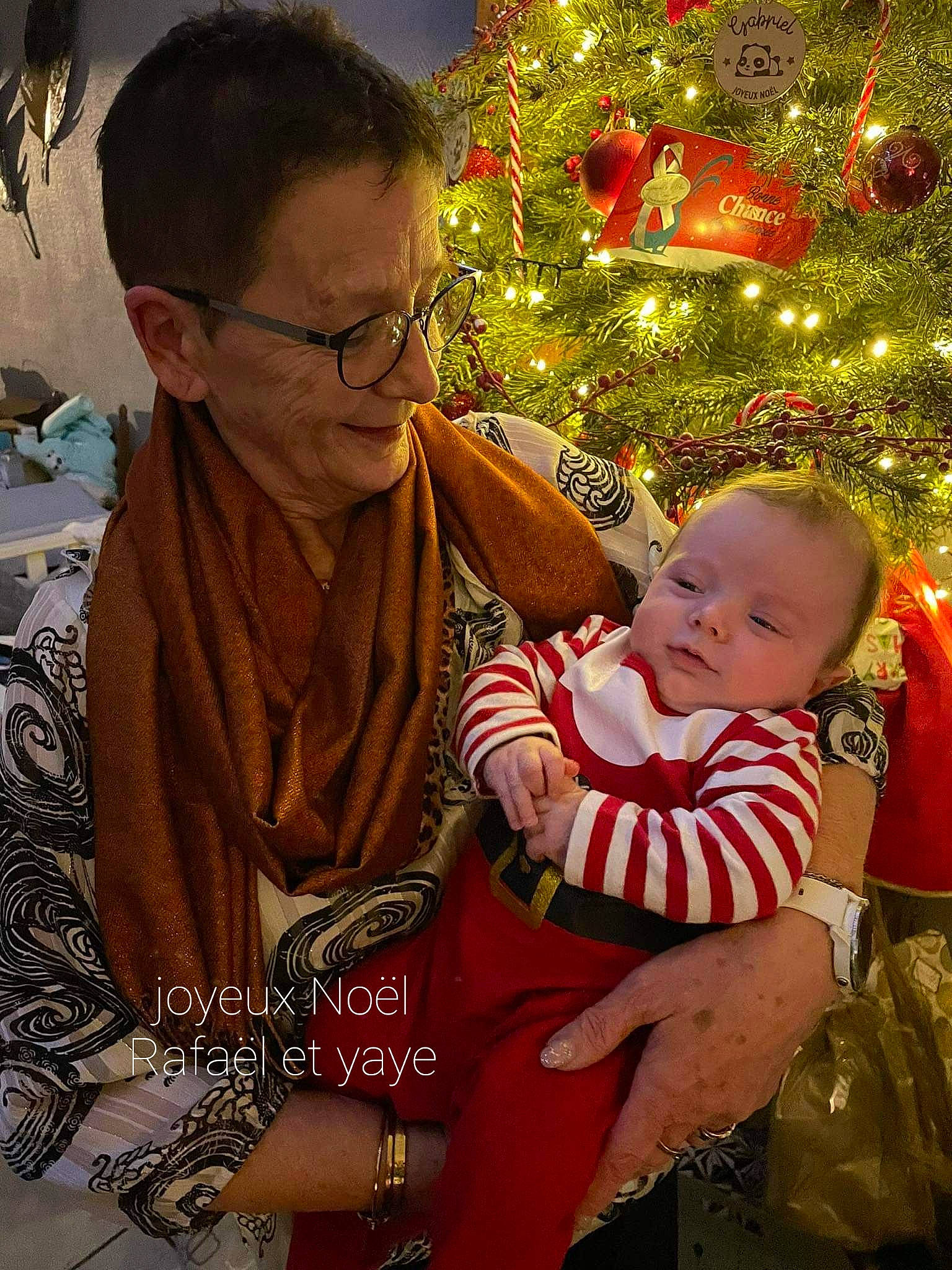 Rafaël participe au concours pour gagner de l'argent avec cette photo : baby, christmas, christmas_decoration, christmas_eve, christmas_ornament, christmas_tree, event, facial_expression, fun, glasses, happy, holiday, jewellery, lap, ornament, people_in_nature, person, smile, toddler, tradition