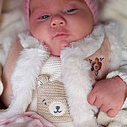 Charlotte participe au concours pour gagner de l'argent avec cette photo : baby, blanket, child, clothing, cozy, cute, cute_expression, face, fur_vest, hand, indoors, infant, knitted_bear, knitwear, pink_hat, portrait, sleepy, soft_texture, warm, wrapped_up