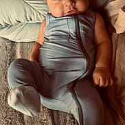 Jett is registered to the contest to win money with this photo: baby, infant, onesie, blue_clothing, blanket, pillow, soft_texture, sleepwear, cute, child, portrait, indoor, resting, cozy, smiling, face, cute_expression, young_child, comfortable, lying_down