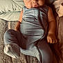 baby, infant, onesie, blue_clothing, blanket, pillow, soft_texture, sleepwear, cute, child, portrait, indoor, resting, cozy, smiling, face, cute_expression, young_child, comfortable, lying_down