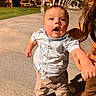 adult_hand, archway, baby, child, city, clothing, curly_hair, expression, holding_hand, night, outdoor, pants, person, shirt, shoes, sidewalk, street_lights, support, urban, walking