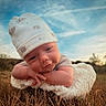 Koltyn is registered to the contest to win money with this photo: baby, infant, hat, bear_pattern, blanket, outdoor, grass, sky, clouds, cute, portrait, child, soft_texture, nature, resting, hands, face, smile, young, peaceful