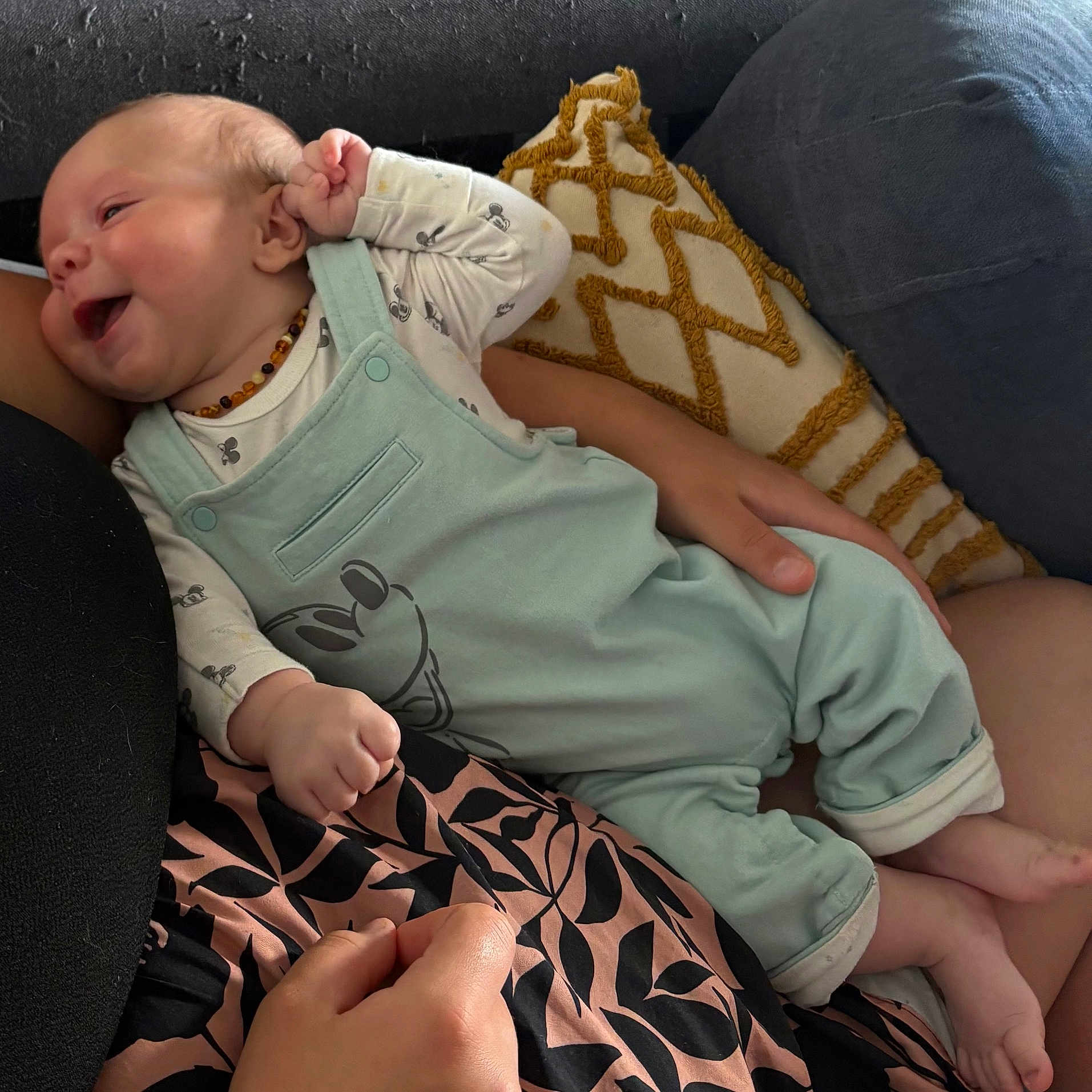 Noah a rejoint le concours — aidez-le/la à gagner de superbes lots ! baby, child, clothing, cozy, cushion, cute, fabric, foot, hand, happy, holding, indoor, infant, mickey_mouse, overalls, pattern, person, relaxing, sitting, smile