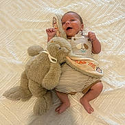 Noah a rejoint le concours — aidez-le/la à gagner de superbes lots ! baby, infant, plush_toy, elephant, striped_clothing, onesie, blanket, soft_toy, happy, smiling, cuddling, lying_down, cute, child, newborn, bedroom, fabric, texture, comfort, cozy