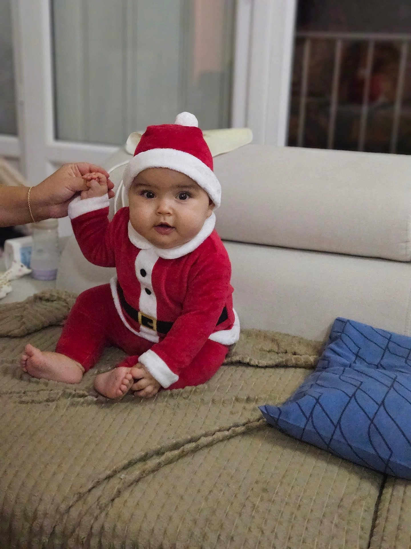 Lyna participe au concours pour gagner de l'argent avec cette photo : baby, child, santa_outfit, red_clothing, hat, indoor, couch, pillow, hand, holding, person, infant, smiling, face, cute, holiday, festive, home, blanket, seated