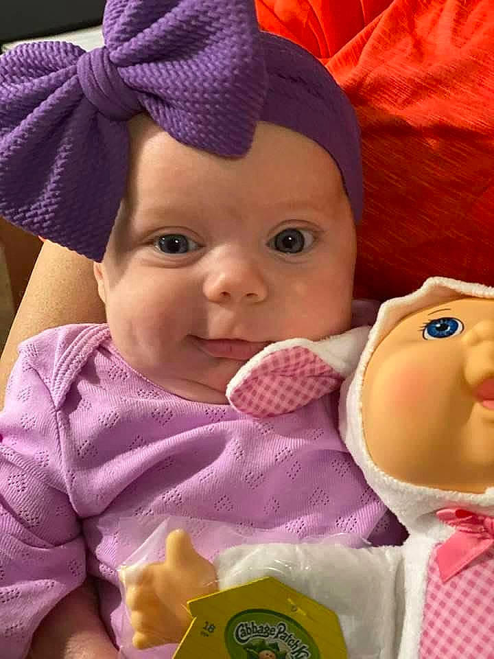 Lilly is registered to the contest to win money with this photo: baby, baby_toddler_clothing, cap, cheek, child, chin, facial_expression, forehead, gesture, happy, headgear, headwear, lip, mouth, nose, organ, person, pink, product, purple