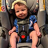 baby, infant, car_seat, child, smiling, headband, blue_clothing, sitting, seatbelt, indoor, cute, small_child, person, happy, foot, toe, fabric, strap, safety, portrait