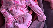 Lorelai is registered to the contest to win money with this photo: baby, blanket, child, clothing, couch, cozy, curious, hand, holding, indoor, infant, pajamas, person, portrait, purple_light, seated, sleepwear, soft_light, warm, young_child