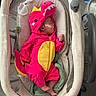 Lorelai joined the competition — help win amazing prizes! baby, infant, dinosaur_onesie, bassinet, sleeping, blanket, toy, floor, play_mat, feet, child, cute, indoors, clothing, pink, yellow, red, headwear, resting, peaceful