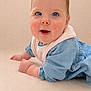 baby, infant, blue_eyes, rosy_cheeks, bib, blue_dress, cute, portrait, closeup, crawling, soft_background, studio_style, skin, face, hands, lying_down, young_child, innocent, smile, adorable