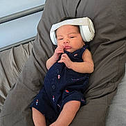 Nicolas joined the competition — help win amazing prizes! baby, infant, headphones, pillow, romper, clothing, foot, hand, face, bed, blanket, resting, cute, child, indoor, person, newborn, relaxed, sleepwear, small