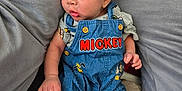 Nicolas is registered to the contest to win money with this photo: baby, infant, child, overalls, clothing, mickey_mouse, blue, cushions, gray, soft, pout, cute, sleepwear, foot, hand, portrait, indoors, comfort, resting, young