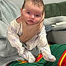Lottie joined the competition — help win amazing prizes! baby, infant, child, hand, face, person, clothing, butterfly_print, sitting, couch, blanket, cushion, indoor, casual, expression, holding, adult, sports_shorts, green, red