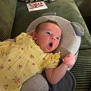 Lottie joined the competition — help win amazing prizes! baby, yellow_dress, pink_mitten, cushion, green_couch, leopard_print_pillow, bag, book, face, infant, expression, plush, person, child, indoor, comfort, resting, closeup, soft_fabric, home