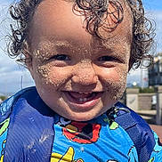 Elijah joined the competition — help win amazing prizes! toddler, child, smiling, curly_hair, sand_on_face, outdoor, blue_sky, sesame_street, colorful_clothing, backpack, happy, sunny_day, portrait, cute, playful, young_child, face, person, daylight, closeup