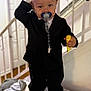 toddler, child, pacifier, black_suit, indoor, stairs, railing, cushion, sneakers, toy, clothing, person, baby, footwear, hand, young_child, standing, home, casual, cute