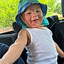 toddler, child, hat, white_tank_top, car_interior, seat, smile, happy, drool, playful, sun_hat, baby, person, young_child, automobile, seatbelt, window, greenery, daylight, casual_clothing
