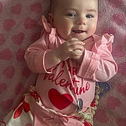 Delilah joined the competition — help win amazing prizes! baby, infant, smile, pink, blanket, heart_pattern, valentine, onesie, pacifier, pacifier_clip, bow, skirt, hands, eyes, face, portrait, lying_down, cozy, soft_texture, cute