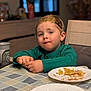 child, toddler, boy, green_sweater, headband, paper_plate, crumbs, food, tablecloth, dining_table, cup, chair, window, blurred_background, portrait, candid, meal_time, face, hands, snack