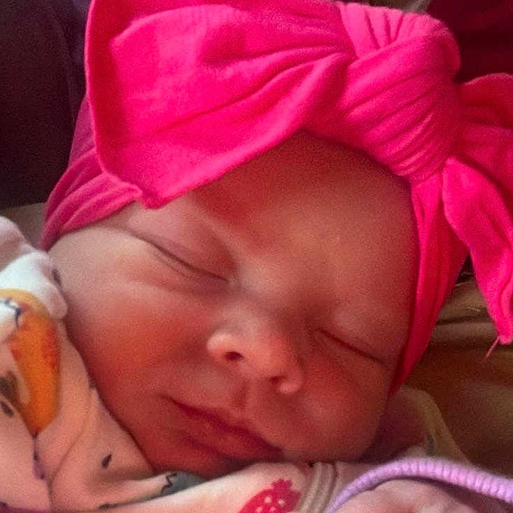 Jersey is registered to the contest to win money with this photo: baby, blanket, bonnet, cap, clothing, face, glove, hat, head, hood, newborn, person, photography, portrait, purple, quilt, skin, sleeping, tattoo, towel