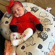 Sophia is registered to the contest to win money with this photo: baby, sleeping, red_outfit, headband, bow, elephant_print, cushion, sofa, blanket, toddler, child, indoor, cute, peaceful, cozy, clothing, footwear, soft_texture, portrait, resting