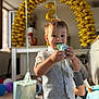 background, balloons, birthday, boy, candy, celebration, child, decorations, floor, gift_bag, happy, indoor, light, number_2, party, person, smiling, toy, vest, window