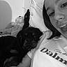 animal, bed, black_and_white, black_dog, casual, cozy, cuddling, dog, face, happy, indoor, person, pet, pillow, portrait, relaxing, selfie, smiling, stuffed_animal, young_adult