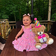 Maria Valentina joined the competition — help win amazing prizes! child, toddler, girl, smiling, happy, portrait, pink_dress, hair_bows, teddy_bear, stuffed_animal, party_hat, outdoor, deck, wooden_table, umbrella, forest, trees, seated, birthday, toy