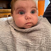 Lily participe au concours pour gagner de l'argent avec cette photo : baby, blanket, child, clothing, couch, cozy, curious, expression, eyes, face, head, home, indoor, infant, person, portrait, soft_texture, warm_colors, wrapped, young