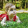 Lily a rejoint le concours — aidez-le/la à gagner de superbes lots ! baby, child, curious, cute, daylight, eyes, face, flower, garden, grass, greenery, head, infant, lying_down, nature, outdoor, portrait, red_clothing, skin, summer