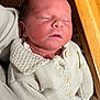 newborn, baby, sleeping, knit_sweater, cream_color, buttons, infant, peaceful, closeup, person, resting, soft_lighting, indoor, wood_surface, handheld, cute, portrait, child, young, warm