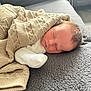 Navy is registered to the contest to win money with this photo: newborn, baby, sleeping, blanket, knitted_blanket, white_clothing, indoor, cozy, resting, infant, soft_light, texture, gray_surface, peaceful, cute, portrait, child, warm, comfort, relaxation