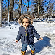 Oliver joined the competition — help win amazing prizes! child, toddler, hood, parka, winter_coat, snow, boots, jeans, outdoor, trees, blue_sky, shadow, sidewalk, backyard, cold_weather, portrait, standing, sunlight, curious_expression, playground