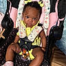 baby, beaded_clip, blanket, car_seat, child, clothing, cute, floor, hair_bows, indoor, infant, pacifier, person, pink_socks, seated, serious_expression, straps, toddler, wooden_floor, yellow_outfit
