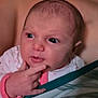 baby, newborn, infant, face, eyes, hand, fingers, expression, blanket, pajamas, onesie, portrait, close_up, indoors, soft_lighting, cuddle, skin, head, gaze, cute