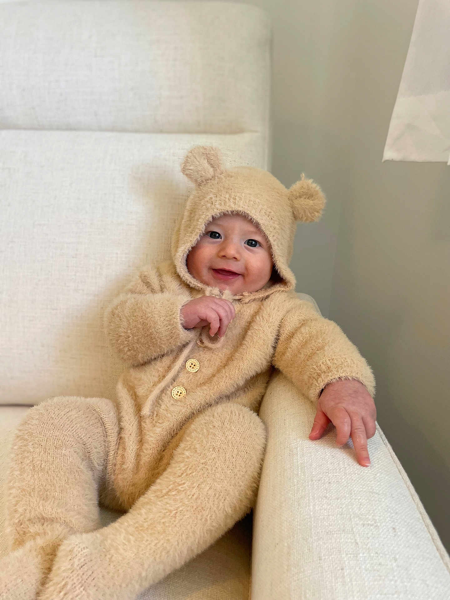 Georgie joined the competition — help win amazing prizes! baby, child, infant, onesie, bear_ears, fuzzy_clothing, smiling, face, armchair, cream_color, cozy, cute, indoor, portrait, happy, furniture, soft_texture, baby_garment, relaxed, seated