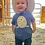 toddler, child, hat, cowboy_hat, jeans, boots, tshirt, seal_graphic, barn, hay, floor, wooden_wall, chair, standing, smiling, indoor, person, cute, happy, casual_clothing