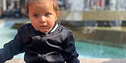 Ziyad participe au concours pour gagner de l'argent avec cette photo : baby, background_blur, black_jacket, blue_jeans, calm, casual_clothing, child, curious, daylight, expression, face, fountain, outdoor, person, pony_tail, sitting, stone, urban, water, young_child