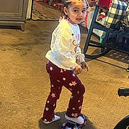 Layla joined the competition — help win amazing prizes! child, indoor, toy_car, braided_hair, colorful_beads, star_pattern, pants, long_sleeve_shirt, carpet, rocking_chair, cushion, toy, furniture, smile, person, floor, play, hair, footwear, home