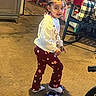 child, indoor, toy_car, braided_hair, colorful_beads, star_pattern, pants, long_sleeve_shirt, carpet, rocking_chair, cushion, toy, furniture, smile, person, floor, play, hair, footwear, home