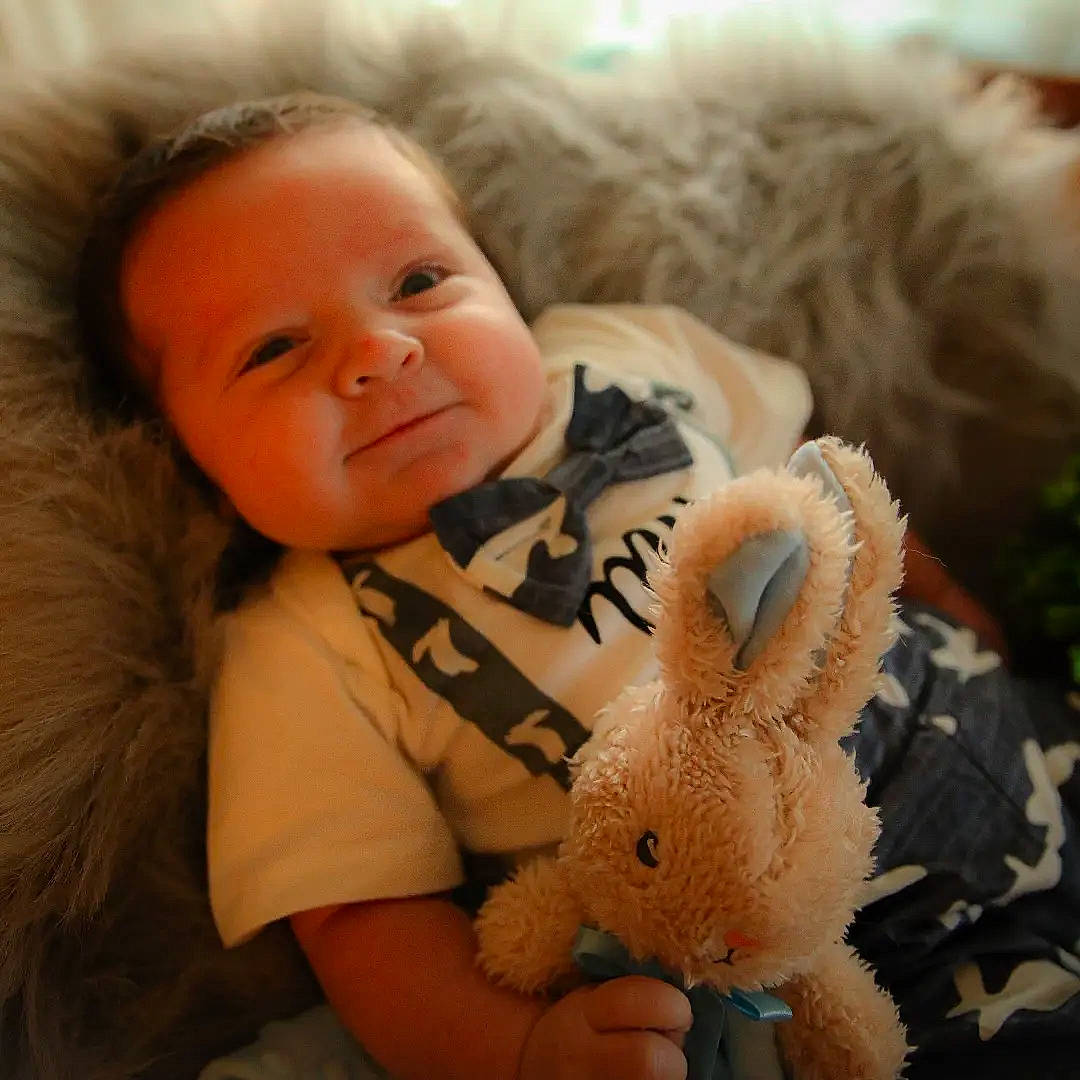 Koda is registered to the contest to win money with this photo: baby, baby_toddler_clothing, cheek, comfort, ear, eye, fawn, finger, happy, head, iris, lip, mammal, nose, organ, person, skin, smile, textile, toy