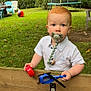 toddler, child, pacifier, toy_helicopter, wooden_fence, grass, garden, outdoor, greenery, chair, table, trampoline, red_hair, white_shirt, play, curious, young_child, daylight, backyard, nature