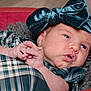 Freya joined the competition — help win amazing prizes! baby, infant, headband, bow, plaid, clothing, blanket, red_background, closeup, face, hands, cute, newborn, portrait, soft_texture, indoors, skin, expression, resting, child